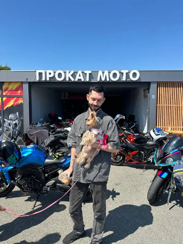 Гость проката с йоркширским терьером на руках у гаража «Прокат мото»