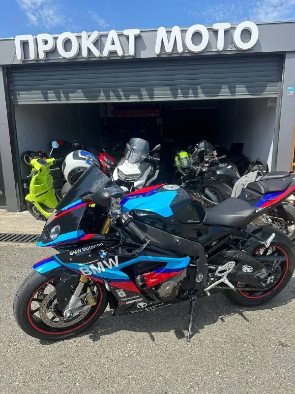 BMW S1000RR у гаража «Прокат мото» на Триумфальной, 1 — за ним ряд мотоциклов